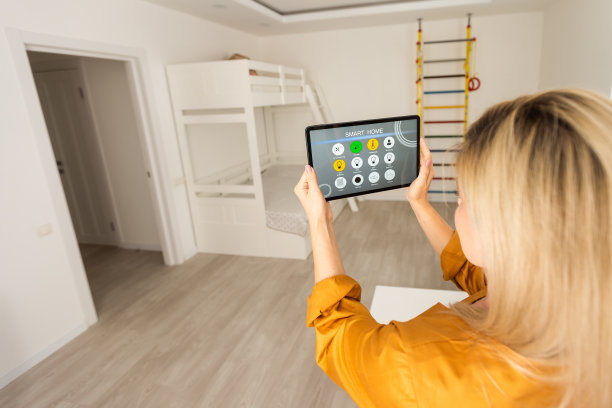 女性使用智能墙壁家庭控制系统。图片下载