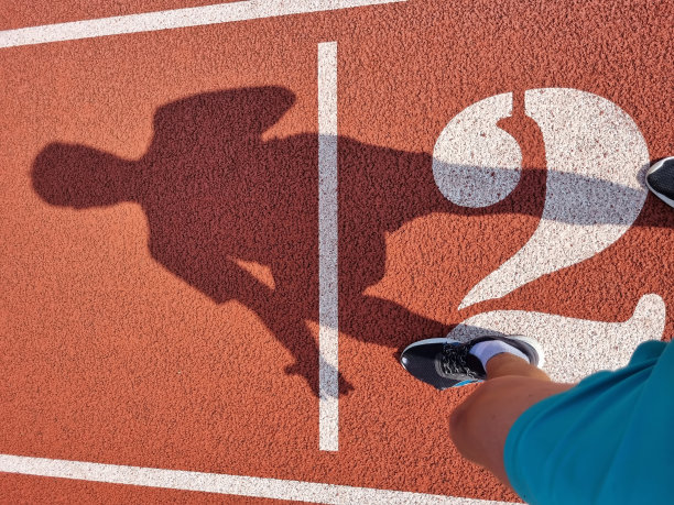一名男子运动员在体育场跑道上开始冲刺的后视图图片下载