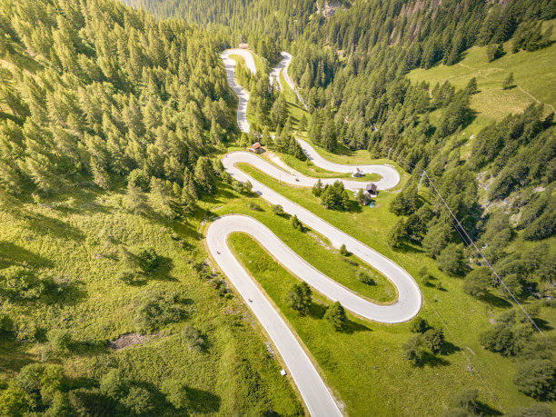 蜿蜒曲折的山路被绿色的森林包围着图片下载