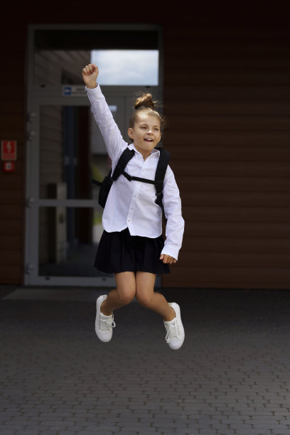 穿着校服的微笑女孩在人行道上奔跑的肖像图片下载