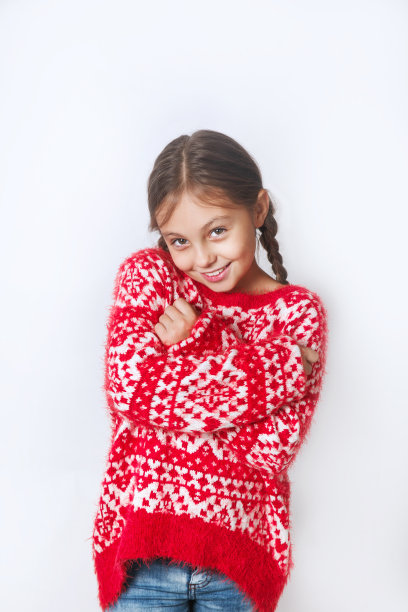 冬天的肖像快乐的孩子与辫子穿着针织毛衣在白色的背景。时尚的概念。图片下载
