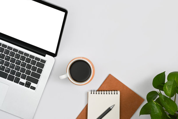 白色的办公桌，笔记本电脑，咖啡杯，笔记本电脑和室内植物。平铺，俯视图。图片下载