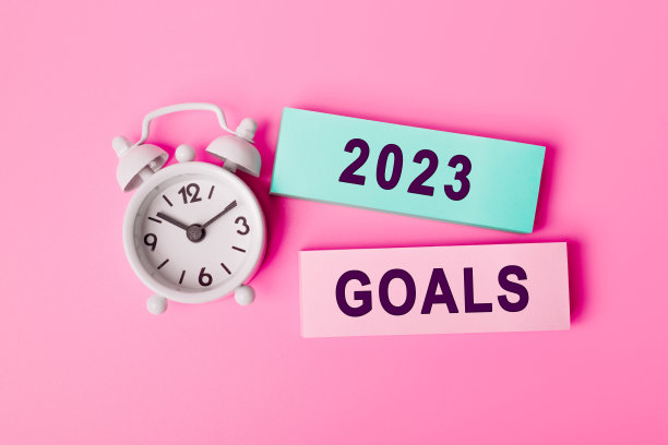 白色闹钟被隔离在鲜艳的粉红色背景上，文字GOALS 2023，写在纸上的笔记。个人日程的特写，俯视图。世界商业、营销、金融的概念图片下载