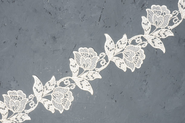 白色蕾丝花和叶子在黑色混凝土背景对角。温柔与粗糙的对比图片下载