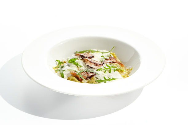 蘑菇馄饨和芝士酱在白色背景上分离。意大利菜-白色盘子上的意式馄饨配牛肝菌和奶油espuma。餐厅菜品配野生菌。图片下载