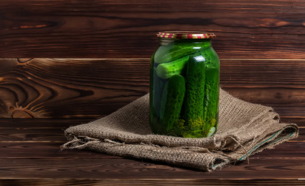 保存、保护。放在旧木桌上的一个罐子里的腌黄瓜。黄瓜，香草，莳萝，大蒜。图片下载