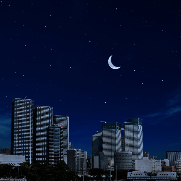 一轮新月从摩天大楼上空升起，映衬着晴朗的天空图片下载