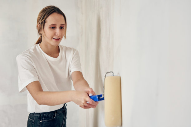 一个年轻漂亮的女人把墙刷成了白色图片下载