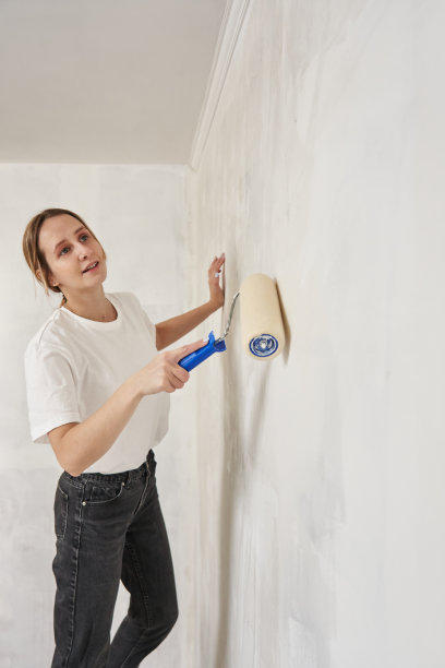 用油漆滚筒在墙上涂油漆的美女侧面画像图片下载