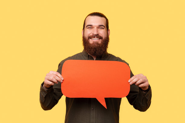 一个留着胡子的年轻男子举着一个演讲泡泡的照片图片下载