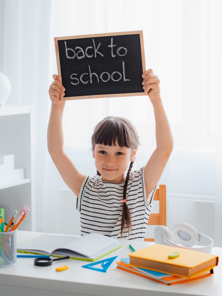 做作业的女生开心地举起一块写有题词的黑板回到学校。图片下载