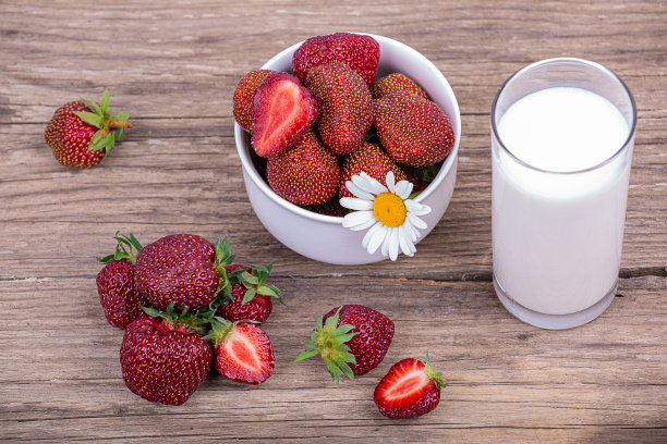 一杯新鲜牛奶和一盘成熟的红色草莓，木制背景，特写图片下载