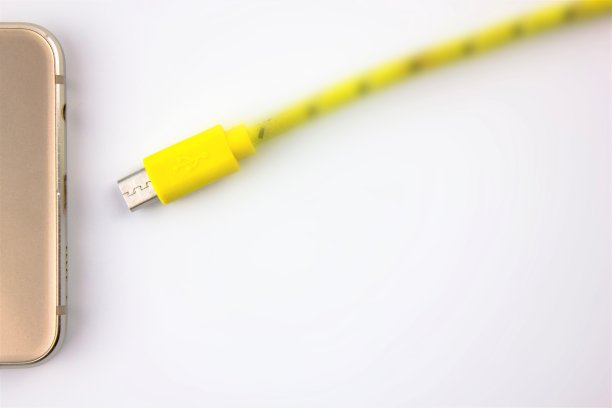 智能手机充电。白色隔离背景下的电池充电线和智能手机。图片下载