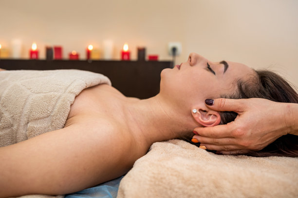 漂亮的黑发少女在按摩院做头部按摩。图片下载