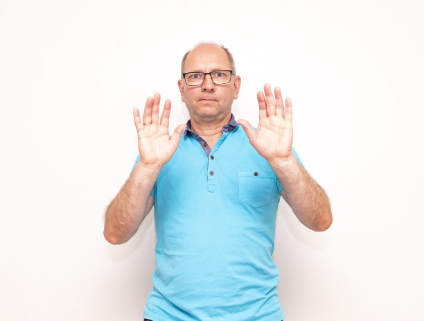 一位中年白人男子举起双手表示拒绝。图片下载