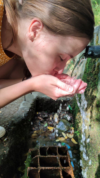 女孩在泉水上用手喝水图片下载