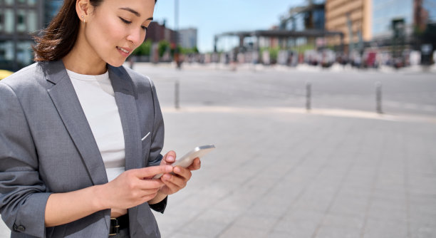 年轻的亚洲女商人在城市街道户外使用智能手机。图片下载