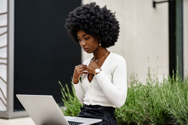 年轻的非洲裔美国女商人坐在城市的长凳上用笔记本电脑工作图片下载