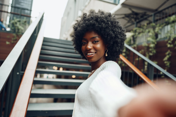 年轻微笑的非洲妇女在城市的楼梯附近摆姿势图片下载