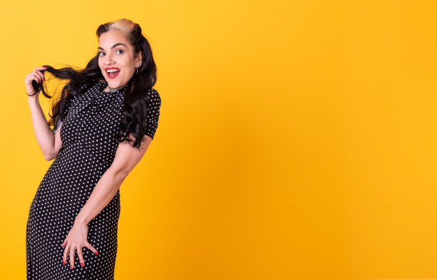 美丽的海报女孩摆到相机在黄色的背景。图片下载