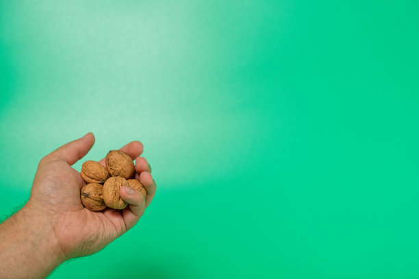 在绿色孤立的背景上，拿着胡桃壳的男人的手图片下载