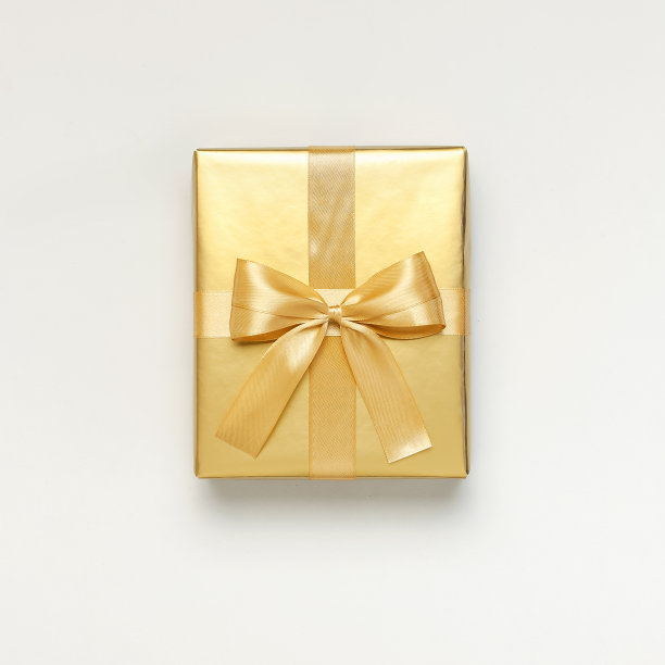 平铺秋日假日概念。金色的礼品或礼品盒上的缎带浅灰色背景俯视拷贝空间。惊喜，祝贺，生日，贺卡图片下载