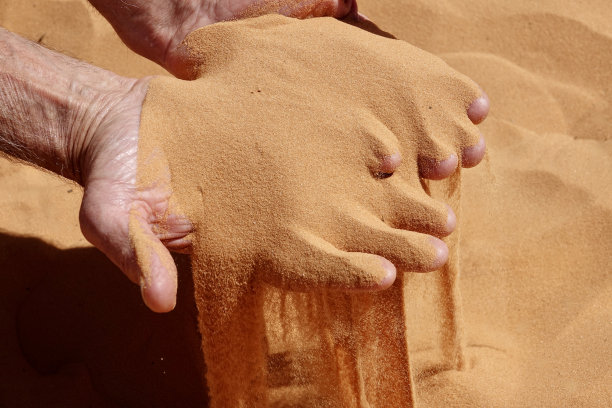 粉红色的珊瑚沙流过他的手指图片下载