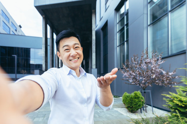 亚洲人在视频通话中使用电话，看着镜头，愉快地挥手致意图片下载