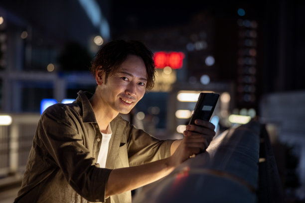 男子夜间在人行天桥上使用智能手机的肖像图片下载