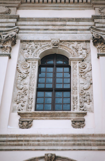 古色古香的巴洛克式窗户，有棕色的木框，灰色的墙上饰有装饰性的灰泥。利沃夫的耶稣会教堂。图片下载