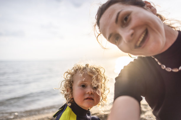 小冲浪者和他妈妈在沙滩上自拍图片下载