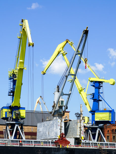 黄色和蓝色油漆的起重机将煤炭装载到港口的一艘散货船上图片下载