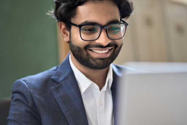 快乐的印度年轻商务男士使用笔记本电脑工作图片下载