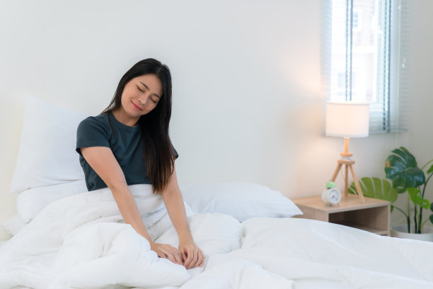 美丽幸福的亚洲女人醒来，在床上醒来(睡)。她在清新的清晨伸展她的手臂，放松宁静的早晨惯例，懒惰的一天休息的概念。图片下载