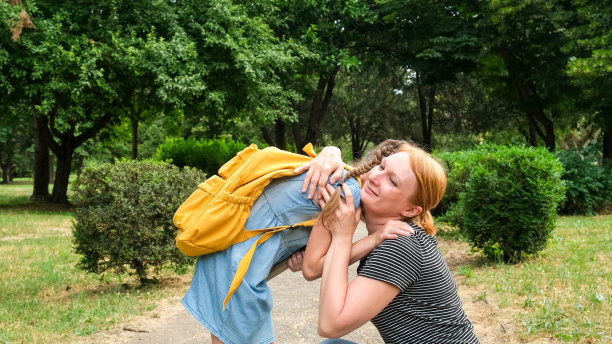 母亲在公园里拥抱她的女儿。回到学校。秋天的第一天图片下载
