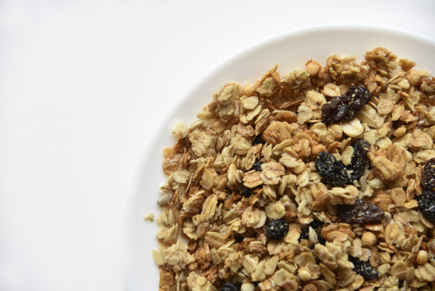 什锦麦片，坚果和葡萄干放在白色盘子里图片下载