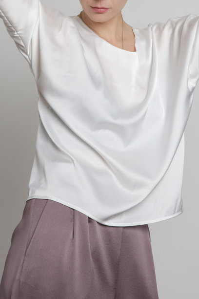 年轻女性模特穿着蝙蝠翼短袖衬衫和宽腿长裤的工作室照片系列。图片下载