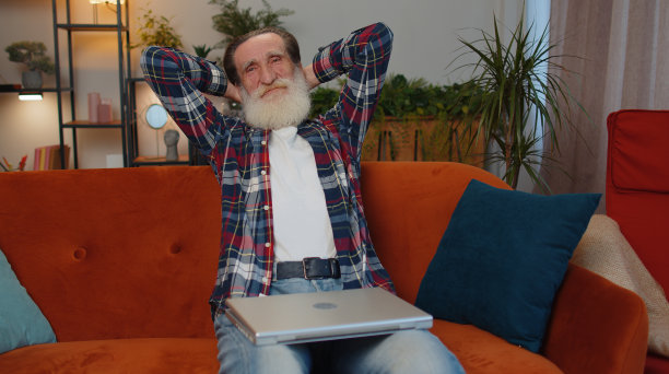 在家里的客厅里，老爷爷下班后坐在沙发上合上笔记本电脑图片下载