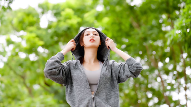 一位穿着夹克的亚洲妇女在公园里健身。健康生活理念，公园户外运动图片下载