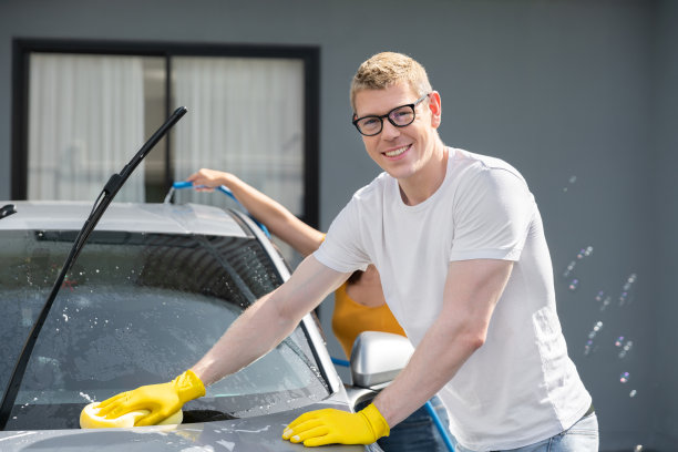快乐的一家人周末在自家车库用喷水和洗发腊清洗汽车图片下载