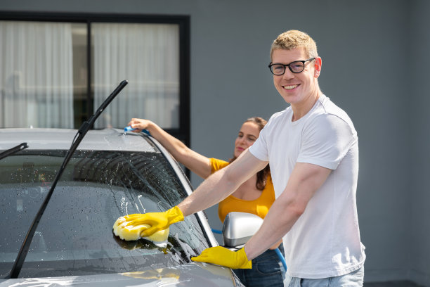 快乐的一家人周末在自家车库用喷水和洗发腊清洗汽车图片下载