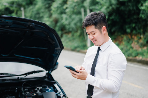 亚洲商人汽车引擎故障他用手机呼叫保险智能手机问题，事故紧急上路概念。图片下载