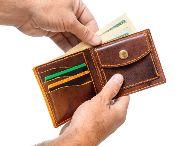 一个男人拿着一个打开的棕色钱包，里面装着钱和信用卡图片下载