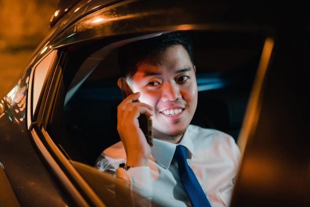 亚洲商人成功的智能手机工作到深夜坐在汽车靠窗的后座图片下载