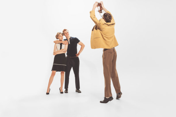 男人的肖像在黄色的复古夹克拍照与美丽的夫妇的老式相机孤立在白色的工作室背景图片下载