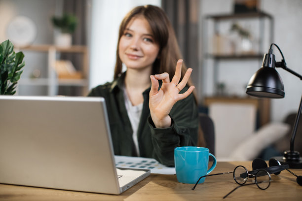 美丽的白人女性与黑色长发坐在桌子上打字的笔记本电脑。图片下载