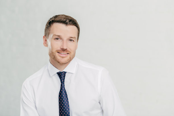 快乐的男性办公室职员带着友好的微笑，穿着优雅，思考未来的计划，参与业务，准备会议，在白色背景下独自摆姿势。专业人领袖图片下载