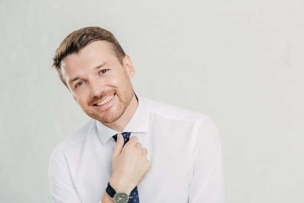 开朗的不刮胡子的男人打着领带，穿着优雅的白衬衫，微笑友好，很高兴在生活中取得成功，繁荣和富有，孤立的白色背景。人领袖图片下载