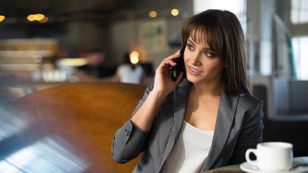 特写照片的一个女商人在商务电话，而她有咖啡刹车在咖啡馆。图片下载