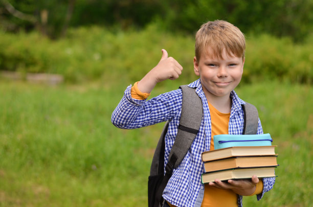 回到学校。一个拿着书和书包的小学生。图片下载